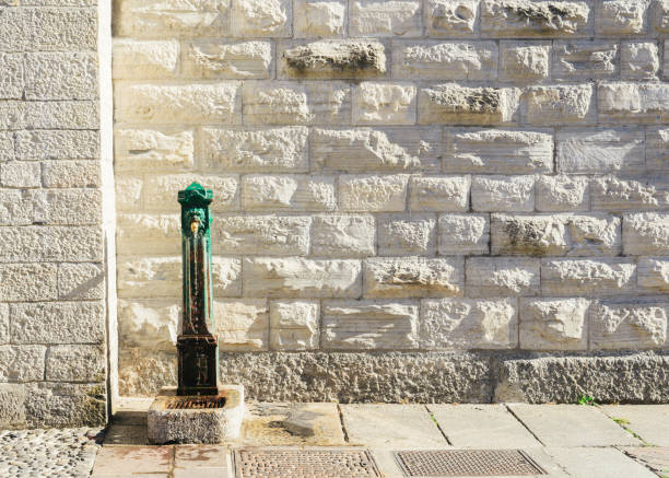 Traditional drinking fountain and brick facade in Como, Italy