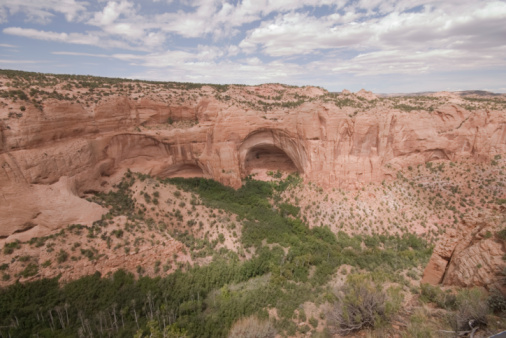 Panoramic view of North Window, South Window, and Turret Arch with beautiful clouds in the sky, small figures of people in the frame emphasize the scale and beauty of this majestic creation, Moab, USA