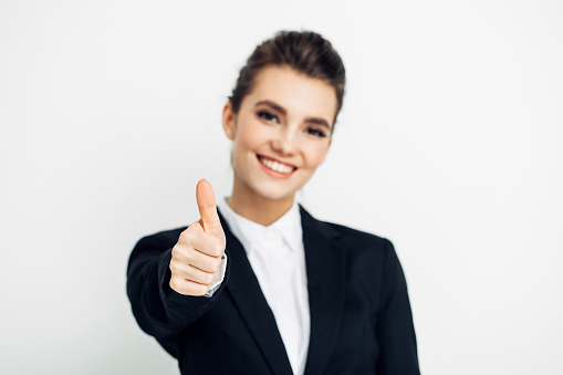 Businesswoman in black suit thumbs up isolated on white