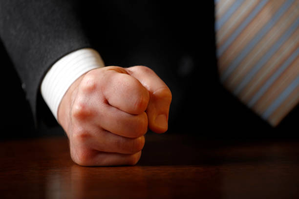 Close-up photo of a businessman (politician) hitting the desk with his clenched fist. Shallow depth of field. Can illustrate the concept of stress, disagreement, anger, etc.