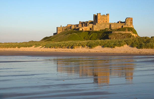 Bamburgh Castle reflects off the water  Bamburgh Castle, waves and reflection Bamburgh stock pictures, royalty-free photos & images