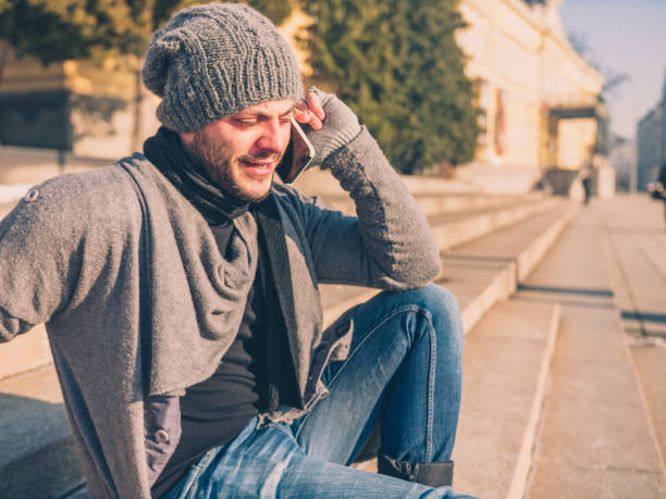 istock Beautiful young man sitting on steps outdoors and talking on his smart phone 913524774