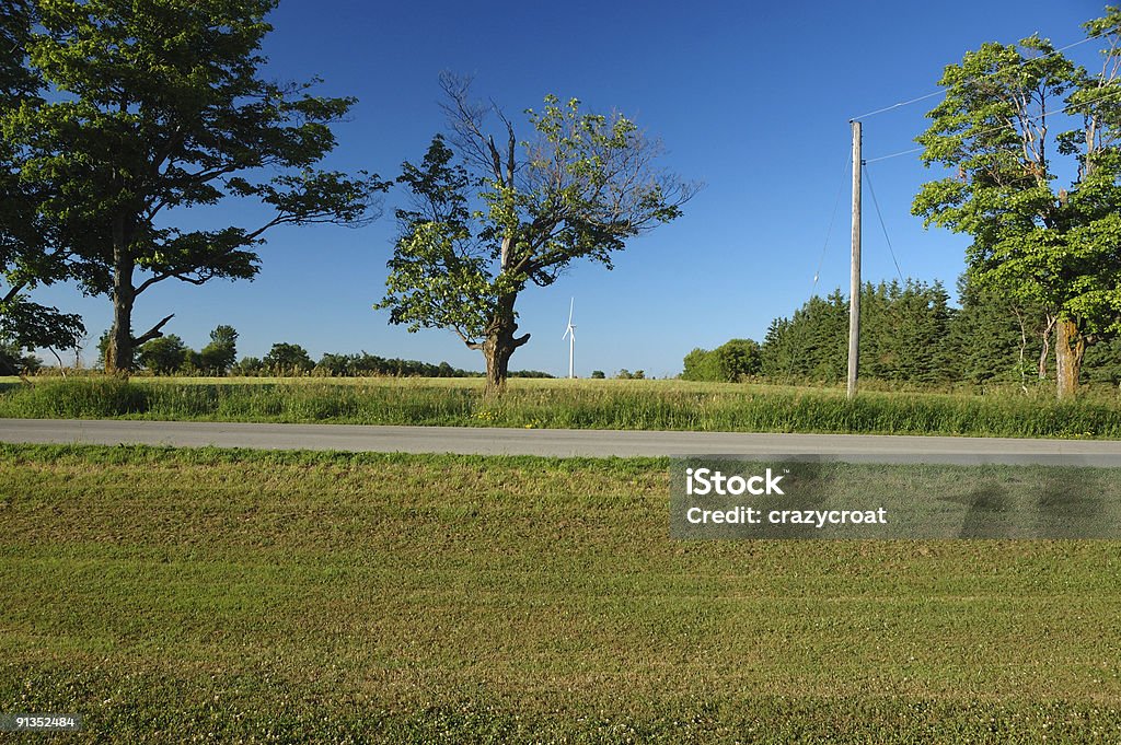 Ontario country road con un molino de viento en el fondo - Foto de stock de Aerogenerador libre de derechos