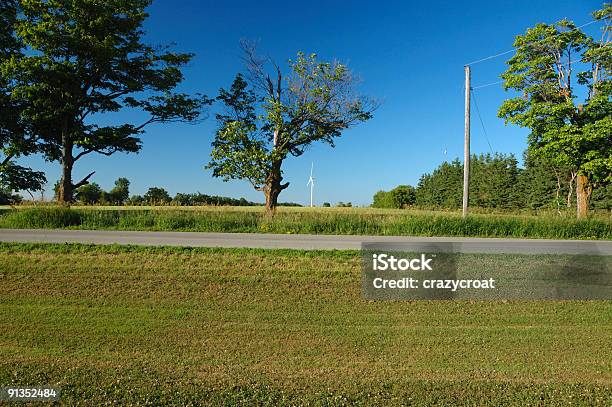 Ontario Country Road Con Un Molino De Viento En El Fondo Foto de stock y más banco de imágenes de Aerogenerador