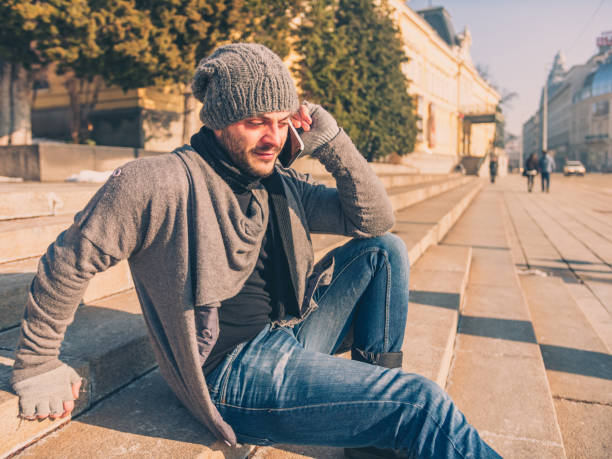 istock Fashionable man sitting on steps outdoors and talking on his smart phone 913524844