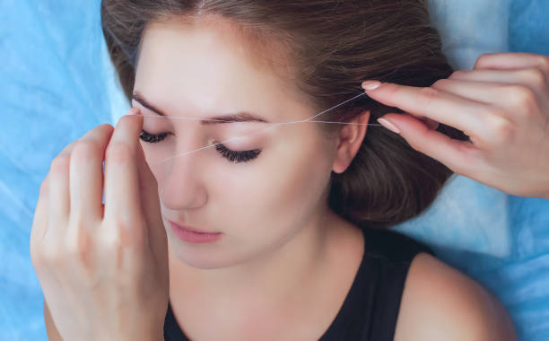 istock A make-up artist plucks an eyebrow with a thread from a beautiful brunette girl 913542814
