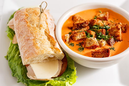 Bowl of cream of tomato soup with Turkey and Cheese sandwich