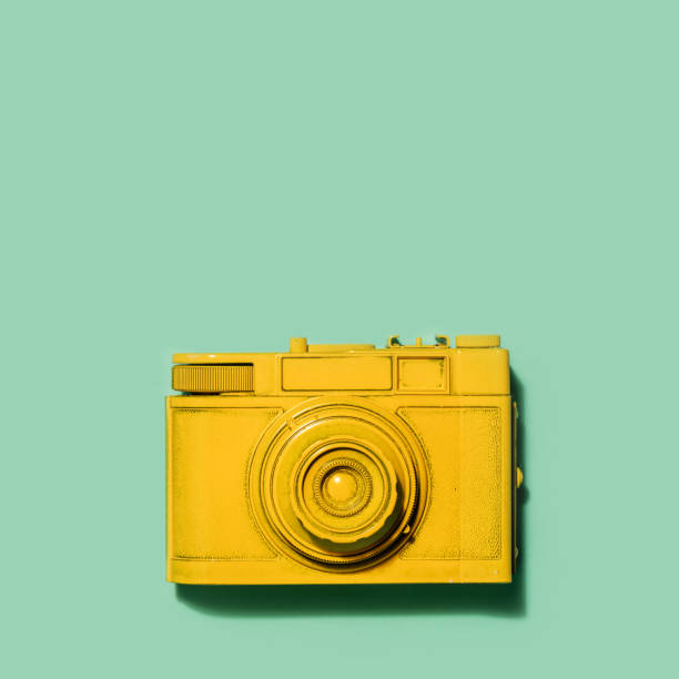 istock Yellow camera laying on a green background 913556894