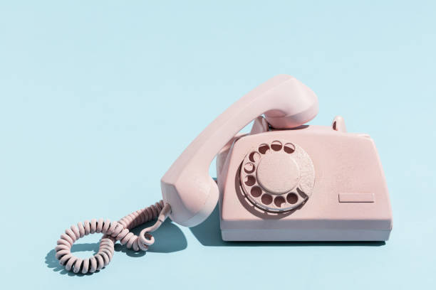 Oldschool pink telephone on a blue background Oldschool pink telephone on a blue background. Telecommunication. Vintage objects. headphones plugged in photos stock pictures, royalty-free photos & images