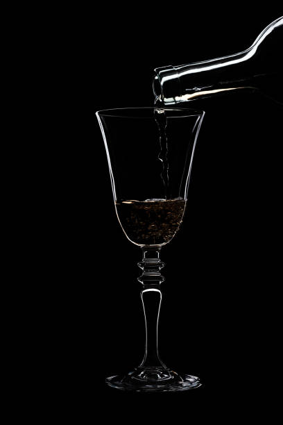 Glass of white wine with threaded on the stem is pouring wine from a bottle of white .