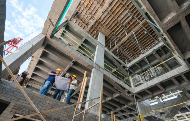 istock Group of construction workers looking at a blueprint at a building site 913566982