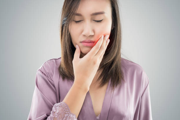 Suffering from toothache. Beautiful young woman suffering from toothache while standing against grey background Suffering from toothache. Beautiful young woman suffering from toothache while standing against grey background jaw pain stock pictures, royalty-free photos & images