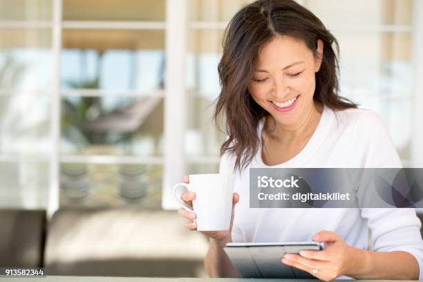 Portrait Of An Asian Woman Smiling Stock Photo - Download Image Now - Digital Tablet, Reading, Women