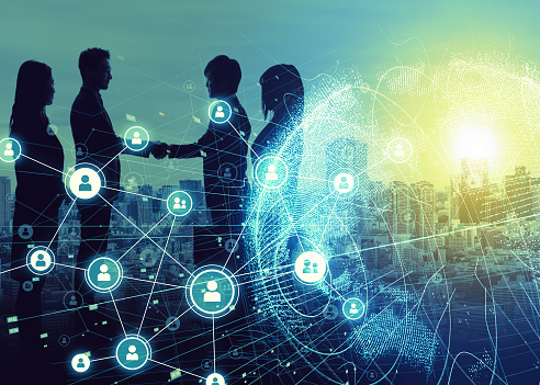Silhouettes of four professionals engaged in a handshake against a city skyline, overlaid with digital network graphics depicting interconnected user icons and data points, illuminated by a glowing sunset.