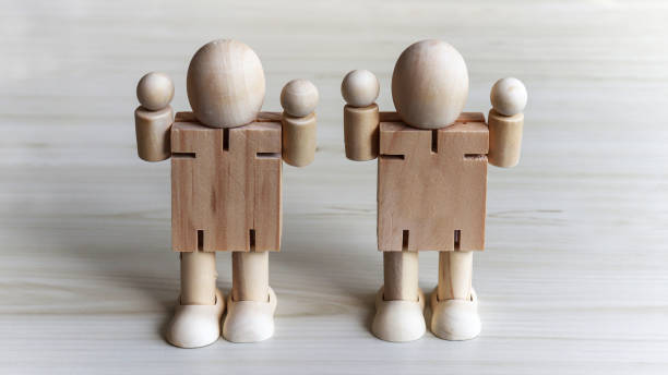 istock Two wooden dolls with its arms raised above. 913587912
