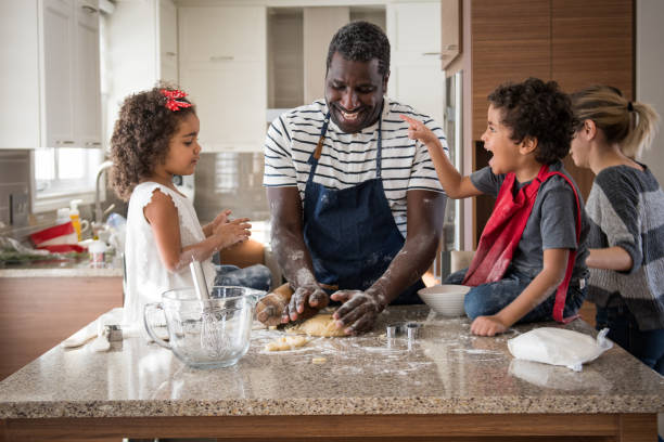 pai haitiano cozinhar com seus dois filhos adoráveis raça mista de 3 e 5 anos de idade - 2 3 years children only group of people enjoyment - fotografias e filmes do acervo