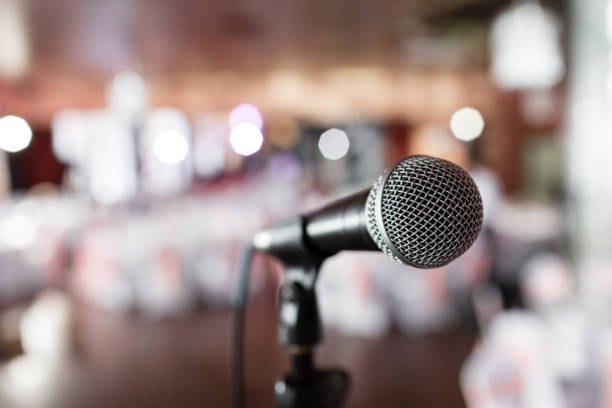 istock Microphone close-up. Focus on mic. Abstract blurred conference hall or wedding banquet on background. Event concept 913616106