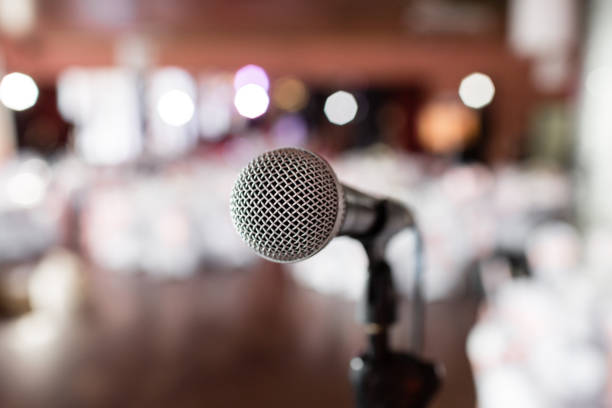 istock Microphone close-up. Focus on mic. Abstract blurred conference hall or wedding banquet on background. Event concept 913616118