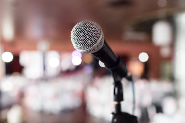 istock Microphone close-up. Focus on mic. Abstract blurred conference hall or wedding banquet on background. Event concept 913616124