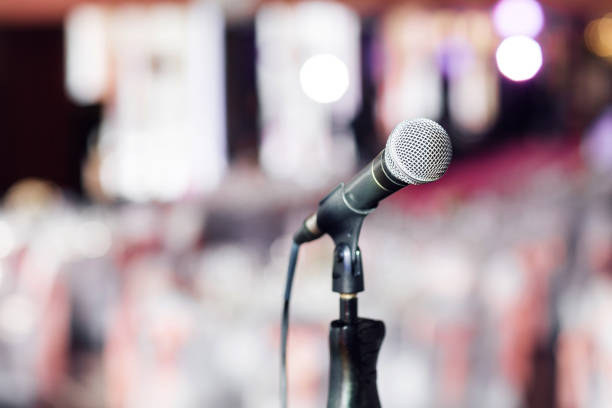 istock Microphone close-up. Focus on mic. Abstract blurred conference hall or wedding banquet on background. Event concept 913616168