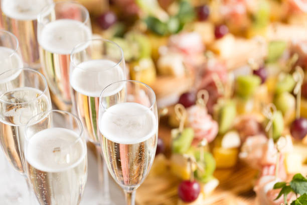 furshet. table top full of glasses of sparkling white wine with canapes and antipasti in the background. champagne bubbles - champagne champagne flute pouring wine imagens e fotografias de stock