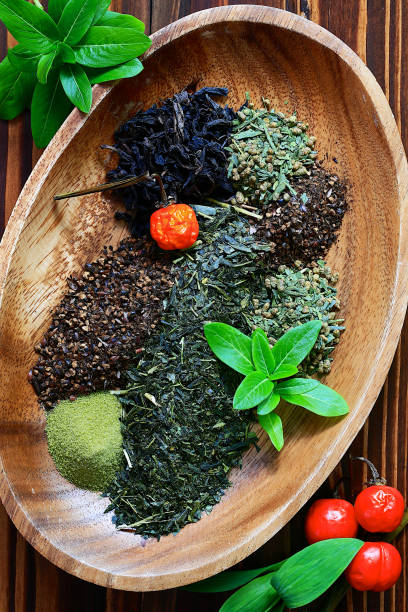 varias hojas de té y frutas rojas secas en placa de madera de forma elíptica, tiro arriba en la mesa de madera - tea chinese tea japan green tea fotografías e imágenes de stock