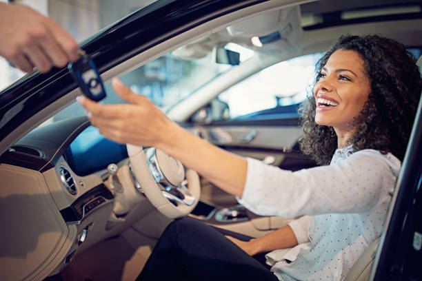 Car dealer is giving key for a new car to a businesswoman Car dealer is giving key for a new car to a businesswoman car key photos stock pictures, royalty-free photos & images