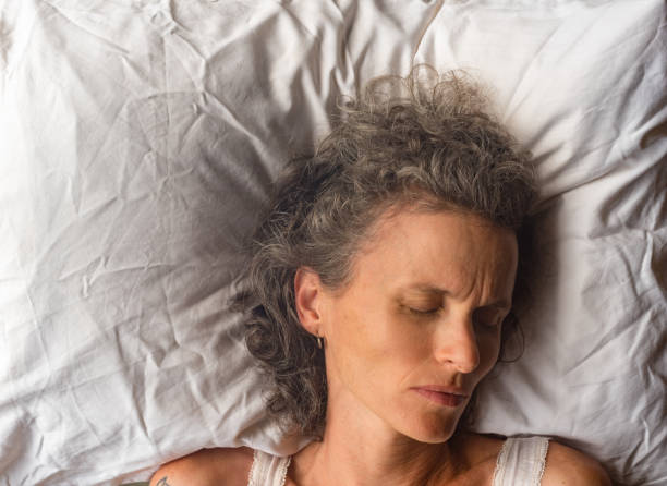 istock Middle aged woman sleeping on pillow from above 913626162