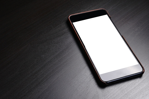 Black smart phone with white screen on dark background.
