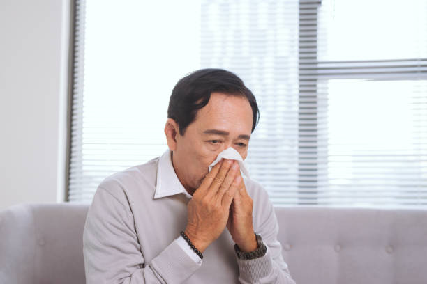 istock Senior man having flu, with paper wipe blowing his nose. 913630936