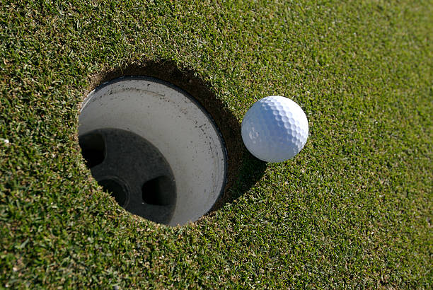 istock golf ball about to roll in hole 91363257