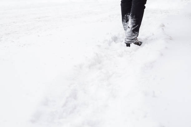 istock Man in black clothes going on white, fresh snow covered sidewalk after snowfall in winter day. City people in blizzard concept. Pavement is not cleaned from snow yet. 913633204