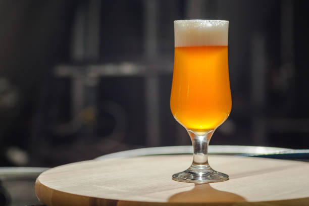 Glass of light beer standing on a wooden tray in an operating brewery