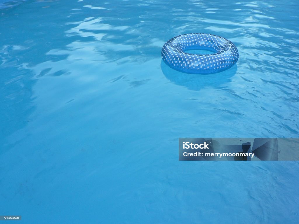 Blue Inner tube in Swimming Pool 2 a blue polka dotted inner tube floating in a swimming pool in summer. Floating On Water Stock Photo