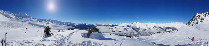 beautiful panoramic landscape on the ski slopes in the snowy mountain under sunny blue sky