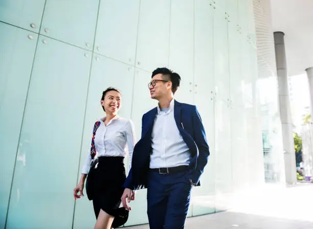 Photo of Asian business people discussing while walking