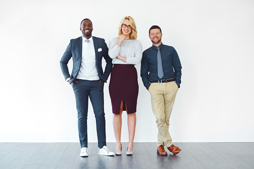 Shot of three well-dressed businesspeople standing against a white background