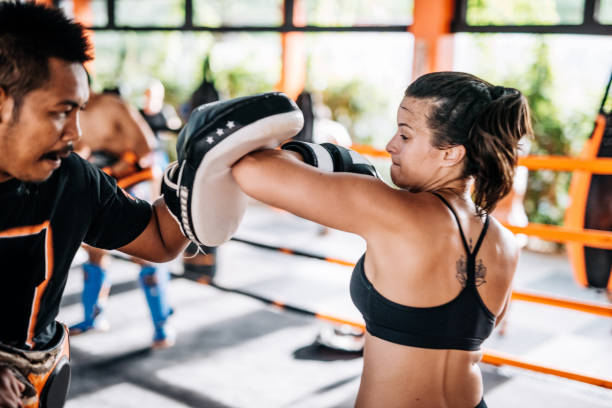istock Teamwork with personal trainer in Muay Thai camp in Thailand - young woman using elbow punch 913654528