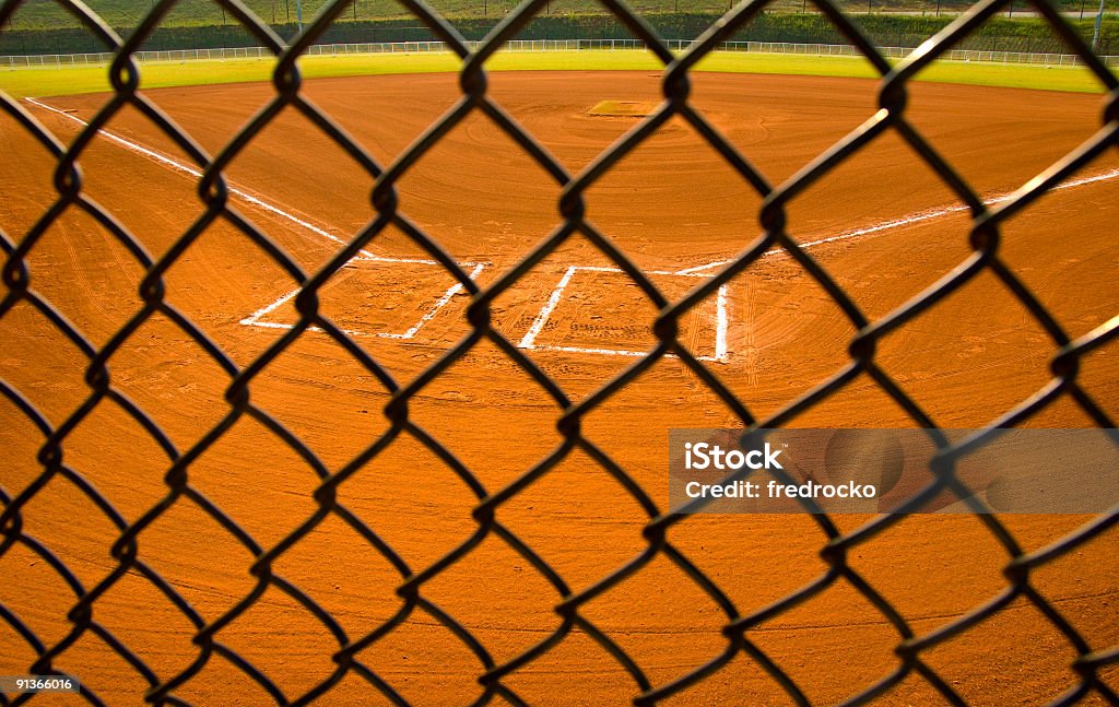 Baseball Field at Baseball Game at Park A DSLR of a Baseball field at a baseball game. the photo is a close up of third base and second base in the infield at a professional baseball game or major league baseball game or little league baseball. Each base is white and the grass is green and the dirt is orange. the lighting is natural sunlight during the day with baseball stadium lighting. there are no baseball players in the photo. the photo is an abstract background with no people at a sporting event.  Baseball - Ball Stock Photo