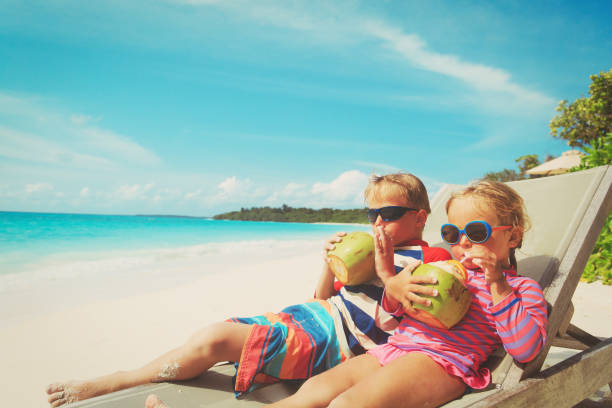 istock little boy and girl drinking coconut on beach 913665552