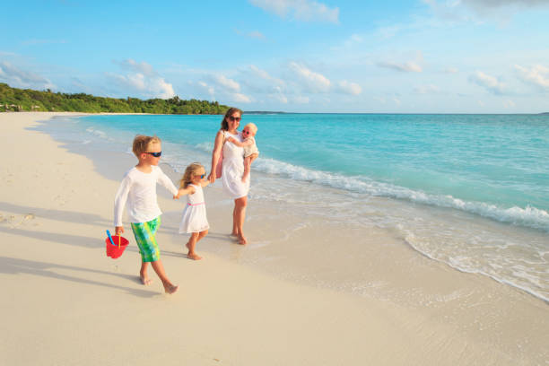 istock mother with little son and daughters walk on beach 913665588