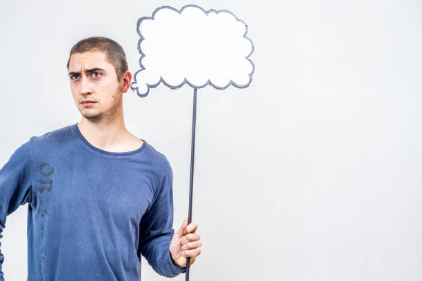 istock Pensive Young Man Holding a Blank Speech Bubble, his Thoughts are Unknown 913676366