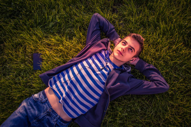 istock Teenage boy lying on grass with phone 913677020