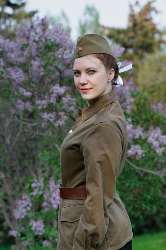 Pretty Soviet female soldier in the form of the Second World war against the background of lilac