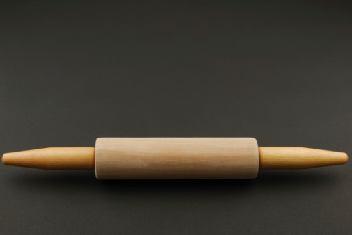 A photo of a rolling pin on a black background.  There is plenty of room for copy.