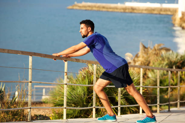 istock fit young man stretching muscles by the sea 913688726