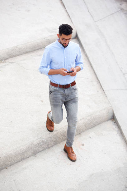 istock Full length young arabic man walking with mobile phone outside 913688978