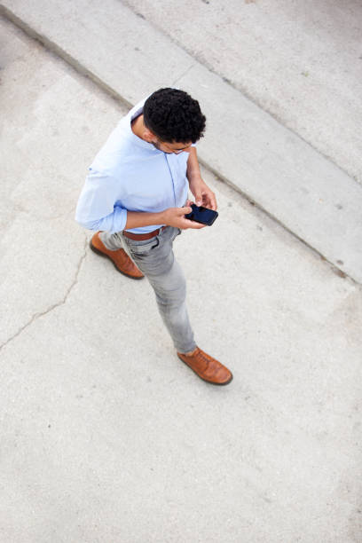 above of man walking and using mobile phone