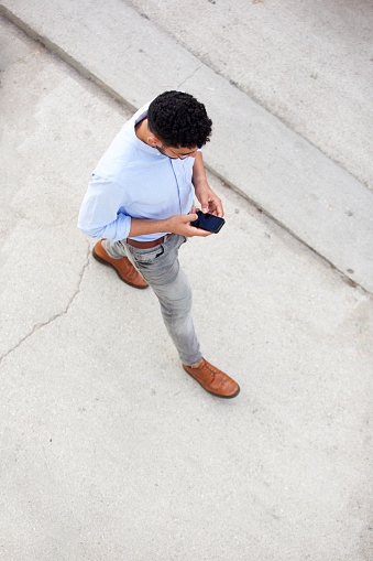 Portrait from above of man walking and using mobile phone