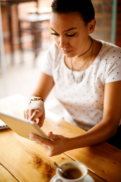 istock Beautiful young woman drinking coffee and using digital tablet in a coffee shop 913689808